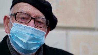 Portrait of an old grandfather in a protective mask against viruses, he looks into the camera. Threat of influenza virus infection. Coronavirus Pandemic COVID-19