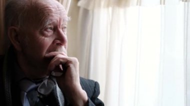 Close up portrait of a lonely old man, an elderly man of an elderly grandfather sitting by the window, feeling pain and in need of help, a depressed pensioner