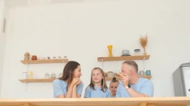 Happy family eating pizza in the kitchen. Family look in blue.