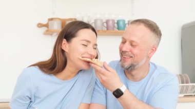 Loving husband and wife in blue T-shirts eating slices of pizza. Happiness concept. Happiness in the little things