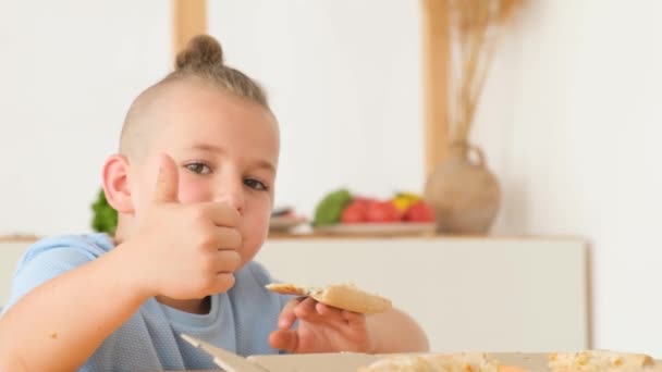 Satisfied Little Boy Tied Hair Eats Pizza Shows Thumb Eating — Wideo stockowe