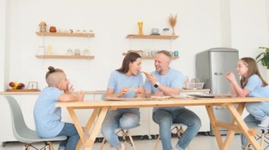 Happy family in the kitchen eating pizza. Happy weekend all together. Family look in blue