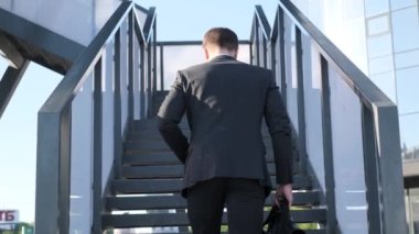  Business man walking up the stairs going to work in the morning, rear view. Slow motion.