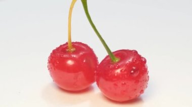 Macro video, two juicy bright red cherries, fresh tasty berries on a white background, rotation of red berries