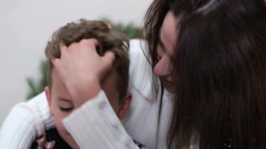 Mom hugs and kisses her son, they are happy and smiling.