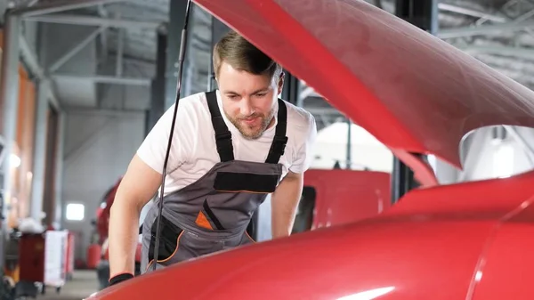 The mechanic inspects the car. The work of a car mechanic in a modern workshop, car service, repair, maintenance concept