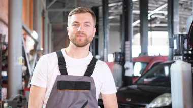Avrupalı bir araba tamircisinin portresi, kameraya bakar ve mutlu bir şekilde güler. Araba servisi konsepti. Metin reklamı için yer