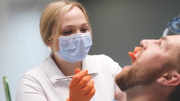 Young Blonde Doctor Treats Young Mans Teeth Patient Sits Dentists — Vídeos de Stock