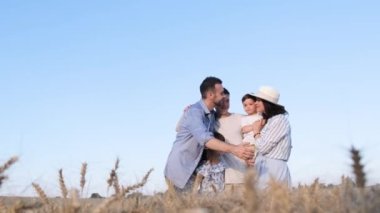 Cheerful parents with three children smiling and standing in a wheat field against a blue sky background. A happy Ukrainian family.
