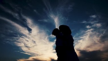 Black silhouette. Happy mother and son hugs against sunset background. Family silhouette. Happiness to be together.