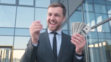 Deli gibi mutlu genç bir adam elinde bir tomar dolarla onları fırlatıyor. Zengin bir bankacı. jack pot