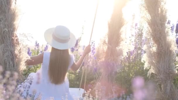 Una Rubia Vestida Blanco Cabalga Columpio Medio Flores Silvestres Sesión — Vídeos de Stock