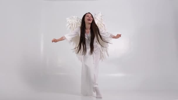 白い背景に白い翼を持つ美しいブルネットの女性 天使の衣装を着た女の子 高品質4Kビデオ — ストック動画
