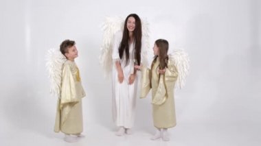 Sihirli video, melek kostümü giymiş aile stüdyoda beyaz bir arka planda dans ediyorlar..