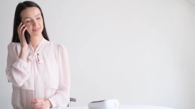 Güzel bir esmer iş kızı akıllı telefon kullanır, iş kıyafetleri giyer. Finans alanında çalışmak