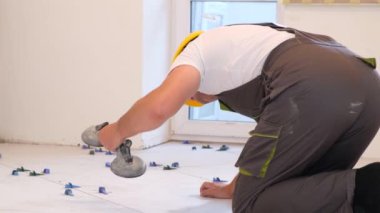 tiler zemine fayanslar yerleştiriyor, evin içini onarıyor. Profesyonel usta, inşaat, onarım, apartman onarımı.