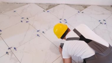 Tulum giyen bir zanaatkar zemine fayanslar döşemiş, evin içini tamir etmiş, inşaat ve apartman onarımı yapmış. Zemine seramik fayanslar yerleştiriliyor - ölçme ve kesme parçaları.
