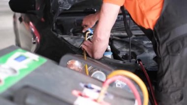 Bir araba tamircisi bir benzin istasyonunda bir araba klimasını tamir eder. Araba havalandırma denetleme servisi. Soğutma şarj sistemi. Araba servisi.