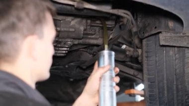 Bir araba tamircisi bir arabanın tekerleklerini yağlar. Servisteki arabanın teknik teftişi. Araba servisinde çalışıyorum.