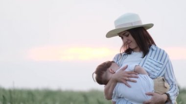 Genç bir anne parkta dinlenirken bebeğini emziriyor. Mutlu bir aile.