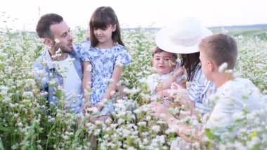 Karabuğday tarlasında genç bir aile. Mutlu şirin bir aile, tarlada birlikte dinlenen çocuklar, sarılıp gülüyorlar. Parkta bir yürüyüş.