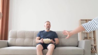 Sevimli Avrupalı bir aile televizyon seyrediyor ve evdeki kanepede patlamış mısır yiyor, birlikte mutlular. Aile sevgisi ve mutluluk kavramı.
