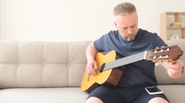 Bir adam kanepede otururken akustik gitar çalar. Evde kanepede dinlenen koca, karısı için şarkı söylemeye hazırlanıyor. Mutlu bir aile.