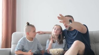 Televizyon seyreden ve patlamış mısır yiyen neşeli bir aile. Aile, evde, kanepede vakit geçirmekten zevk alıyor. Yüksek kalite 4k video