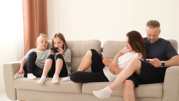 Американская Семья Родители Маленькие Дети Смеются Используя Смартфон Гаджет Расслабляясь — стоковое видео