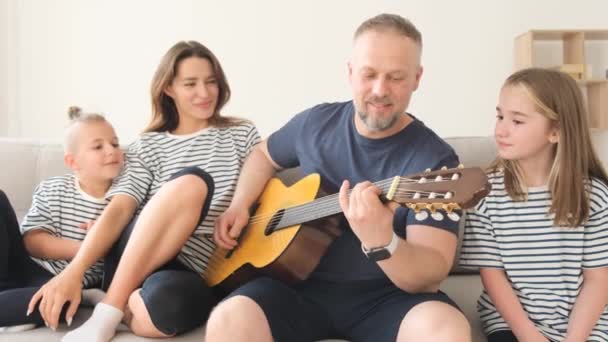 Papá Tocaba Guitarra Para Familia Mientras Estaba Sentado Sofá Relajándose — Vídeos de Stock