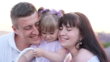 Genç bir aile gün batımında parkta piknik yapıyor. Bir çocuk babasıyla oynuyor. Parktaki yeşil çimlerin üzerinde bir aile. Yüksek kalite 4k video