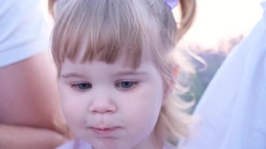 Ailesinin kollarında otururken lezzetli böğürtlen yiyen bir çocuğun yakın çekimi. Aç çocuk.