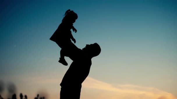 父親のシルエットが娘を投げつけた 公園で子供と遊んでいる子供 小麦畑のシルエット 幸せな家族 子供の夢のコンセプト — ストック動画