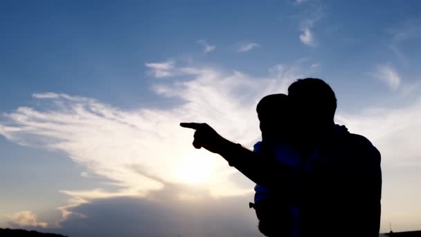 父親の腕の中で幸せな子供 日没の背景に家族の抱擁 少年と父親のシルエット 高品質4Kビデオ — ストック動画