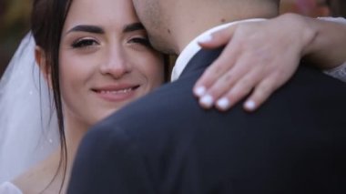 Güzel bir çift gelin ve damat, sarı sonbahar yapraklarında duvar. Avrupa tarzı düğün, mutlu beyaz yeni evliler, öpüşüp sarılıyorlar.