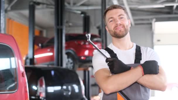 一个迷人的笑容可亲的美国汽车修理工站在汽车修理厂的背景下 拿着汽车钥匙的画像 快乐的员工 — 图库视频影像