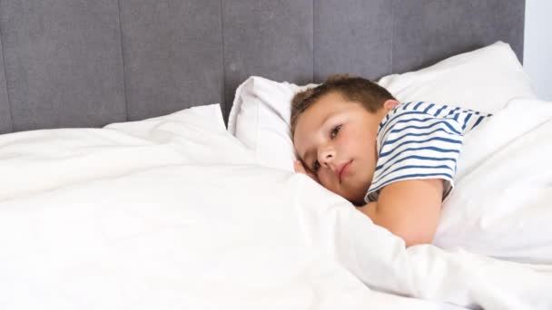 少年は横で寝ていた ベッドで寝ている子供 6歳から7歳の少年はベビーベッドで眠りにつく 4Kビデオ — ストック動画