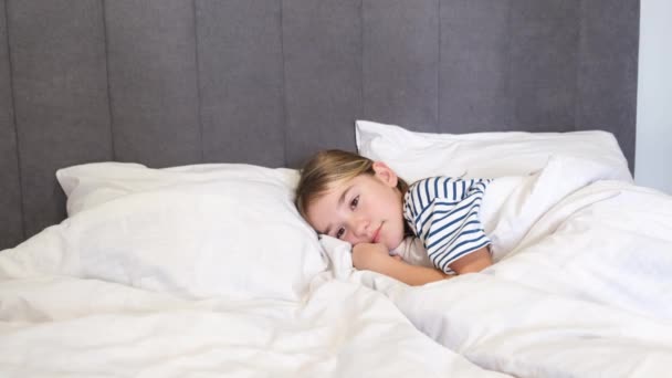 小さな女の子がベッドで横になって寝ている 8歳から9歳の少女がベビーベッドで眠りにつく 4Kビデオ — ストック動画