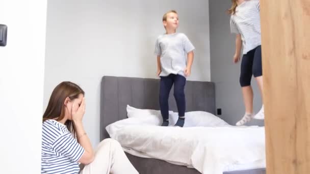家で遊んでいる騒々しい活動的な子供たちのために疲れ いらいら 疲れを感じて 頭痛を持っている若い母親 — ストック動画