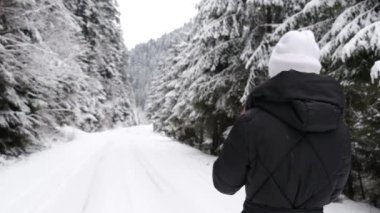 Kışın dağlarda eğlence ve turizm. Karla kaplı güzel Noel ağaçları. Bir kadın ormanın ortasında yürüyor, süper yavaş çekim 240 fp.
