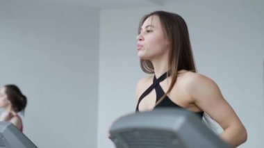 Kardiyo çalışması, spor salonunda genç bir kadın, dayanıklılık eğitimi, koşu bandında koşan güzel bir kız atlet. Spor motivasyonu