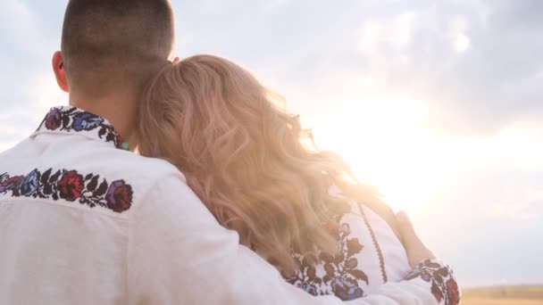 一个美丽的视频一个乌克兰家庭恋爱在绣花衣服 夕阳西下坐在一起拥抱的幸福夫妻 — 图库视频影像