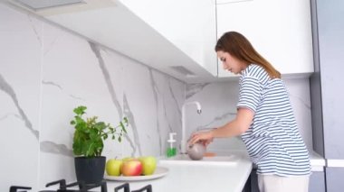 Genç Amerikalı anne kız ve oğlu mutfakta eğleniyor, lavaboda elma yıkıyorlar. Aileyle zaman geçirmek, sağlıklı yemekler. Mutlu bir aile.