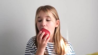 7 yaşında bir kız kırmızı sulu bir elma yiyor. Meyveli sağlıklı yemek. Lezzetli bir elma