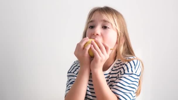 7歳の少女が梨を食べている 自宅で健康的なフルーツスナック 子供たちは黄色のジューシーな梨を食べる 高品質4Kビデオ — ストック動画