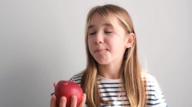 Kırmızı elma yiyen gülümseyen tatlı bir kızın portresi. Lezzetli olgun meyveler. Elmaların C vitamini