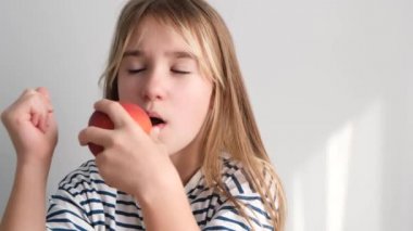 7 yaşında bir kız sulu, olgun bir şeftali yiyor. Meyveli sağlıklı yemek, bir çocuk sarı bir şeftali yer. Yüksek kalite 4k video