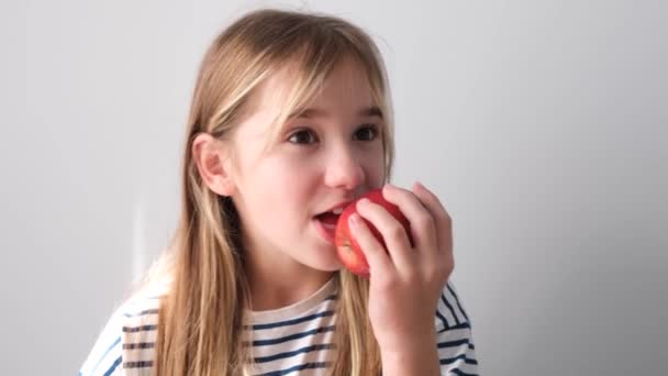Linda Niña Está Comiendo Una Gran Manzana Roja Jugosa Video — Vídeos de Stock