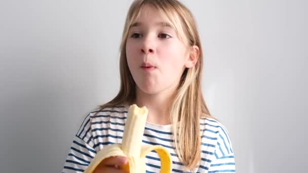 Uma Menina Sorridente Feliz Está Comendo Uma Banana Deliciosa Isolada — Vídeo de Stock