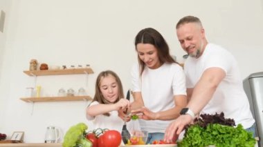 Mutlu gülümseyen aile sabah birlikte kahvaltı hazırlıyor evde mutfakta. Yüksek kalite 4k video